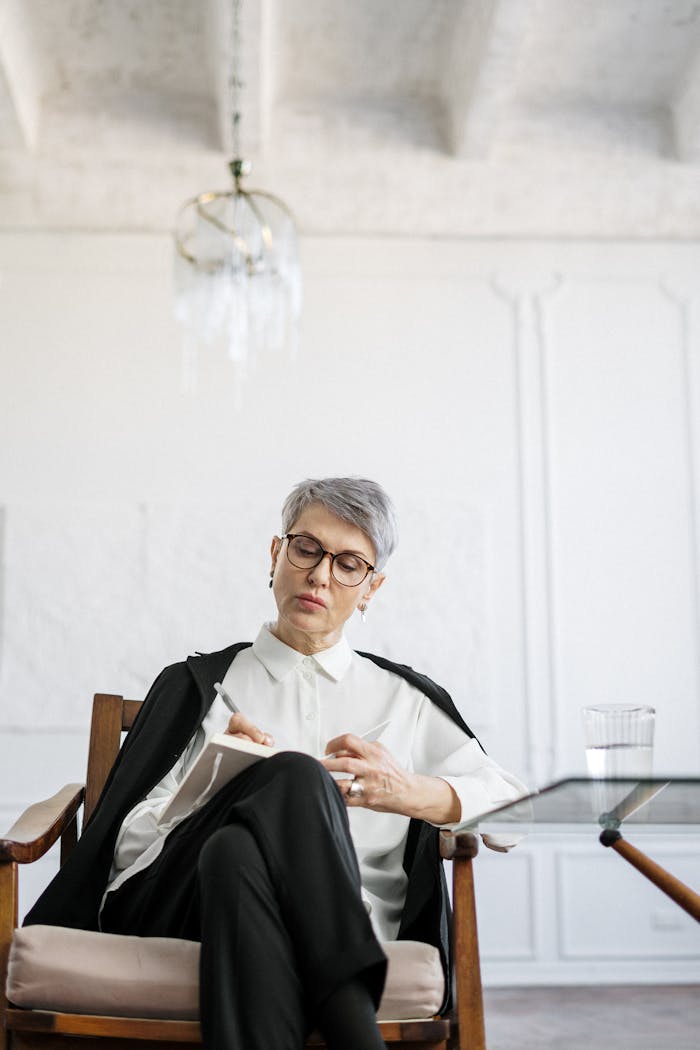 services-03 A mature woman ponders deeply while sitting in a modern office setting, reflecting on her thoughts.