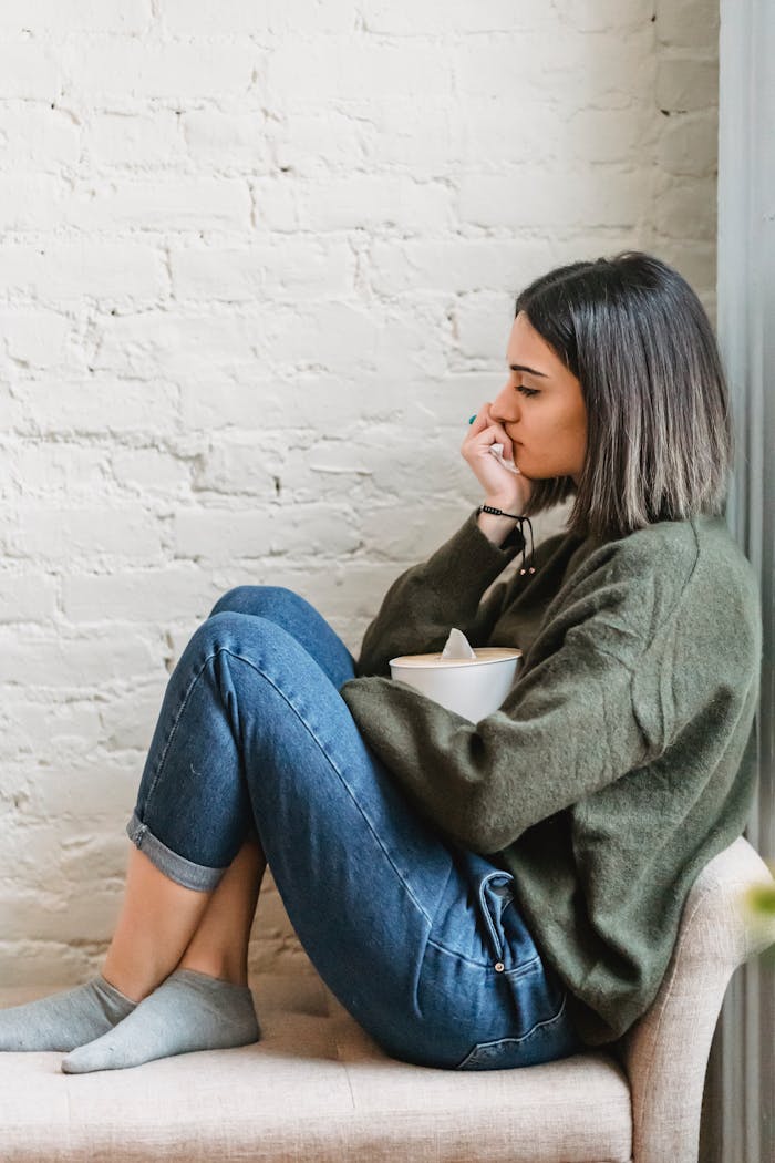 The Art of Drawing Readers In: Your attractive post title goes here Young woman sitting in a pensive mood with tissues, expressing contemplation and emotion.