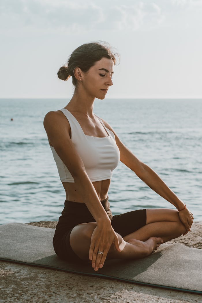 Crafting Captivating Headlines: Your awesome post title goes here Adult woman practicing meditation on a yoga mat by the sea, enjoying calmness outdoors.