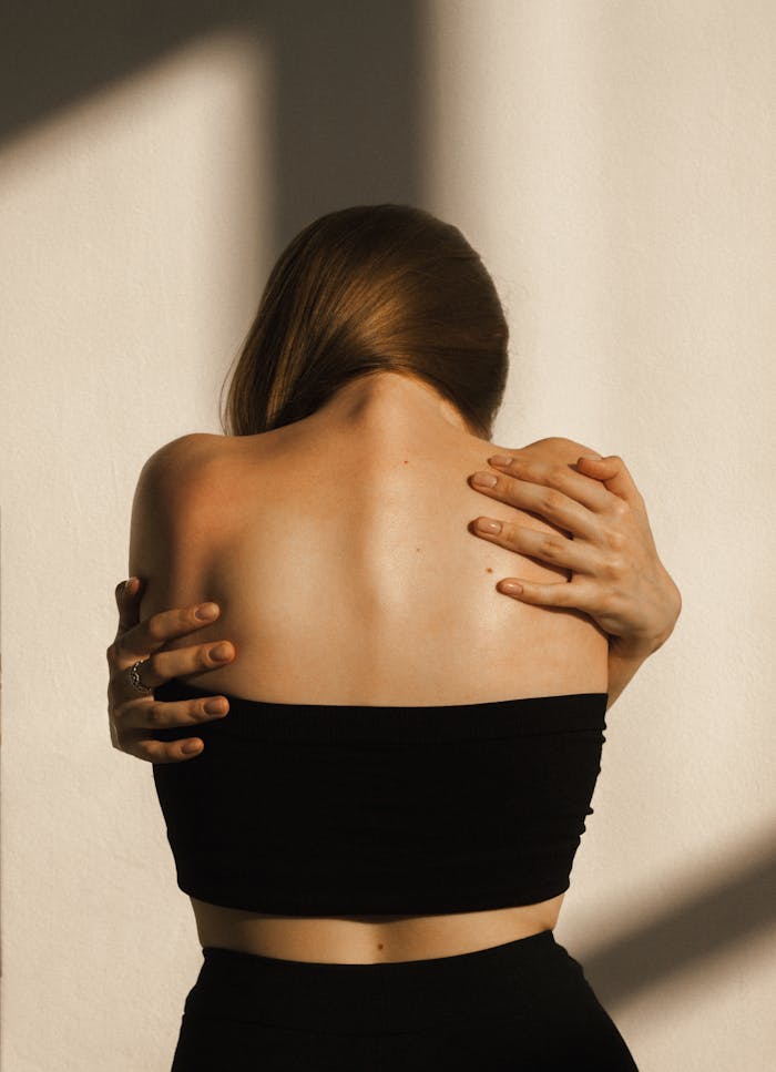 Mastering the First Impression: Your intriguing post title goes here A woman in a black tube top embraces herself, creating a sense of warmth and solitude.